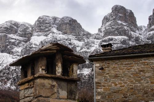a stone building with a mountain in the background at Konaki Hotel in Papigko