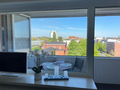 a room with a desk with a computer and a large window at Wilhelms Havenkoje - gemütliches Innenstadtappartment in Wilhelmshaven