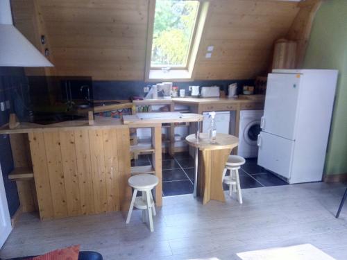 Il comprend une cuisine équipée d'un réfrigérateur, de tables et de tabourets. dans l'établissement Maison Bois 