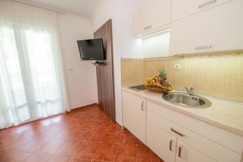 a kitchen with a sink and a television on the wall at Guest House Medin in Petrovac na Moru