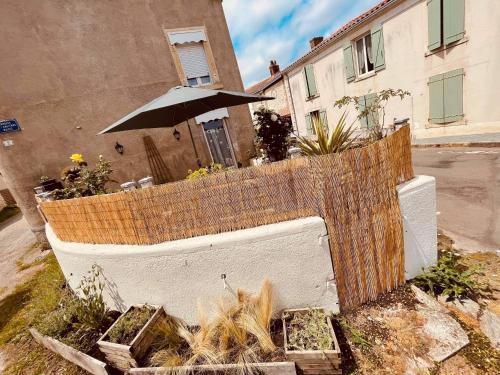 a fence with an umbrella in front of a building at charmante maison de village renovée in Bazoges-en-Pareds