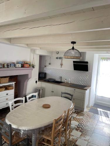 une cuisine avec une table et des chaises dans une pièce dans l'établissement charmante maison de village renovée, à Bazoges-en-Pareds