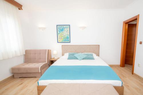 a bedroom with a large bed and a chair at Guest House Medin in Petrovac na Moru