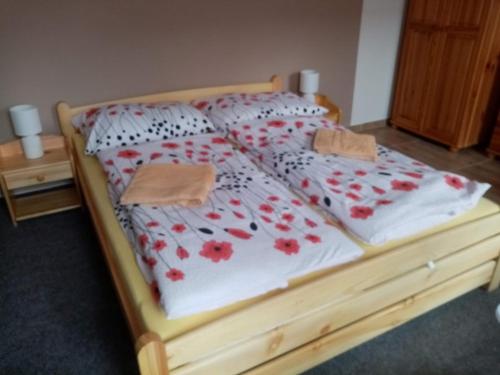 a wooden bed with red flowers on it at Penzion Alenka Valtice in Valtice