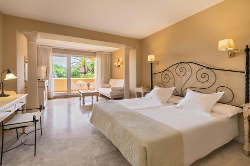 a bedroom with a large white bed and a desk at Hotel Guadalmina in Marbella