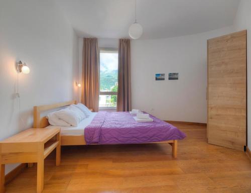 a bedroom with a bed with a purple blanket and a window at Seaside Rest Apartments in Budva