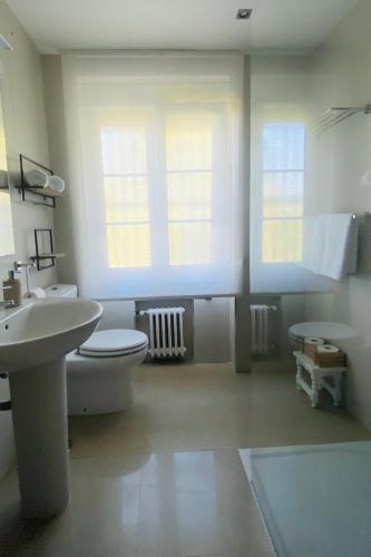 a bathroom with a toilet and a sink and two windows at Casa Vacacional Galiana in Avilés