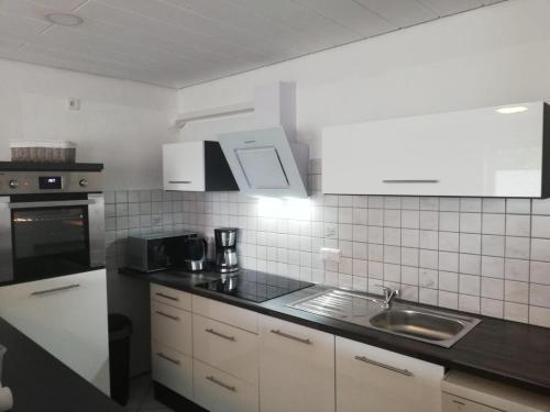 cocina con armarios blancos y encimera negra en Ferienhaus Domus, en Xanten