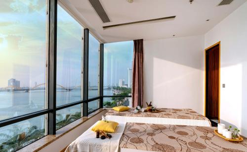 two beds in a room with large windows at Brilliant Hotel - Afternoon Tea Inclusive in Da Nang