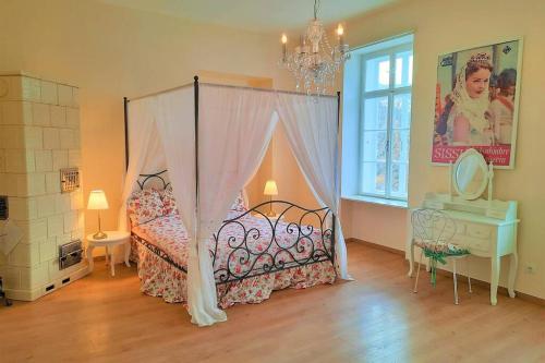 a bedroom with a canopy bed and a table and a window at Sisi-Schloss Rudolfsvilla - Duo in Reichenau