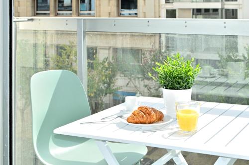 a white table with a plate of food and orange juice at Holihome Rambla 24 in Alicante