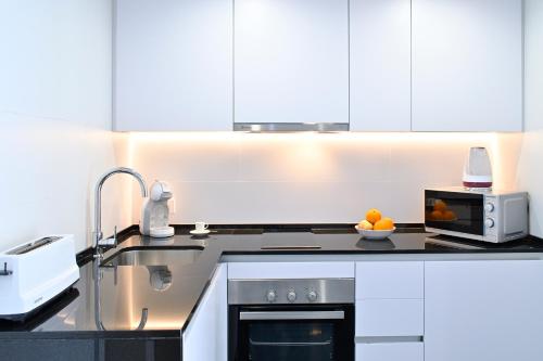 a kitchen with white cabinets and a sink and a microwave at Holihome Rambla 24 in Alicante