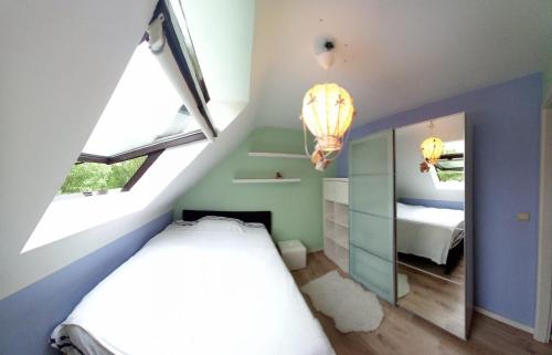 ein kleines Schlafzimmer im Dachgeschoss mit einem Bett und einem Spiegel in der Unterkunft Les prussiens in Wavre