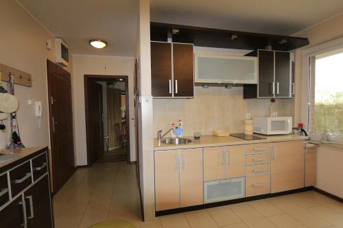 a kitchen with white cabinets and a sink and a microwave at Lazurowa in Krynica Morska