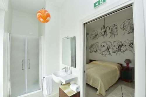 ein Bad mit einem Bett, einem Waschbecken und einem Spiegel in der Unterkunft VAARAK in Bosa