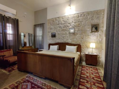 1 dormitorio con cama y pared de piedra en Mi'ilya CHOCOLATE HOUSE Guest house, en Mi‘ilyā