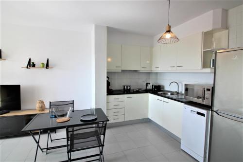 ロザスにあるGlobal Immo 2189 Rocmar 3 3 Cのキッチン(白いキャビネット、テーブル、冷蔵庫付)