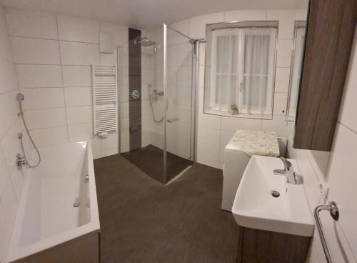 a white bathroom with a shower and a sink at Ferienhaus Laimerbauer in Faistenau