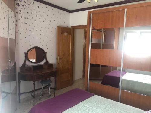 a bedroom with a bed and a desk with a mirror at Apartamento en la playa in Adra