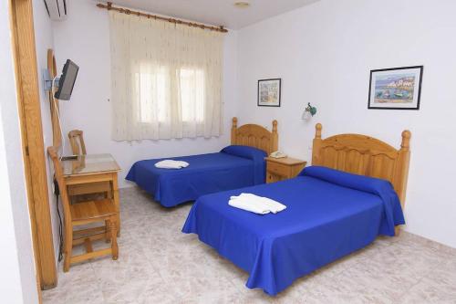 1 Schlafzimmer mit 2 Betten, einem Tisch und einem TV in der Unterkunft HOTEL DON FELIPE in Carboneras