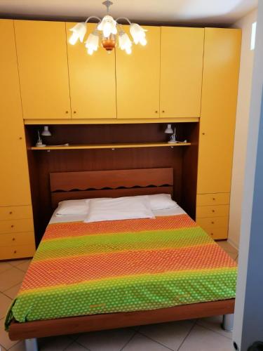 a bed in a room with yellow cabinets at RESORT VILLAGE AQUA MARINA FAMILY - Daily Rooms Tidying - CocktailsBar- Pet Friendly - with Hypermarket - Delivery Restaurant-Pizzeria - Room Breakfast with supplement - Ultra Fast Wi-Fi - Play Area for children - Olympic Swimming Pool - Parking in Caorle