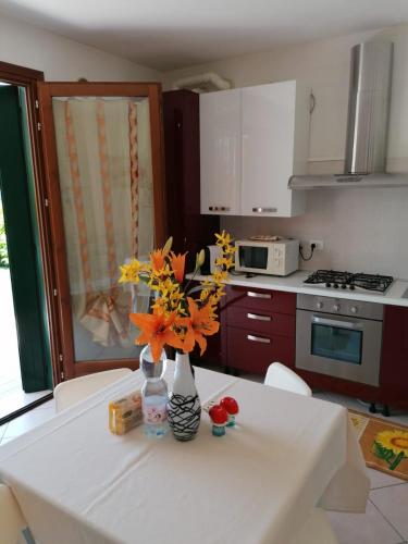 a kitchen with a table with a vase of flowers on it at RESORT VILLAGE AQUA MARINA FAMILY - Daily Rooms Tidying - CocktailsBar- Pet Friendly - with Hypermarket - Delivery Restaurant-Pizzeria - Room Breakfast with supplement - Ultra Fast Wi-Fi - Play Area for children - Olympic Swimming Pool - Parking in Caorle
