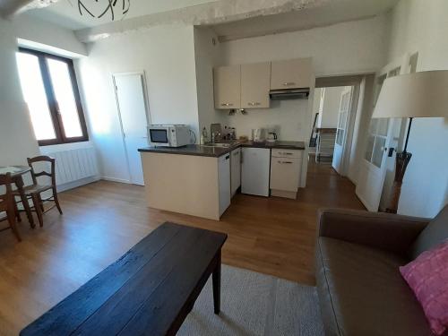 une cuisine et un salon avec un canapé et une table dans l'établissement Appartements - Charme, jardin et vue imprenable en plein coeur de St-Cirq, à Saint-Cirq-Lapopie