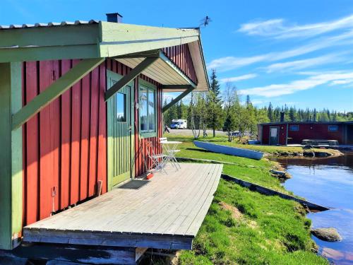 a house with a wooden deck next to a body of water at Camp Alta Kiruna in Kiruna