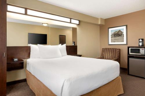 a hotel room with a large bed and a chair at Microtel Inn and Suites by Wyndham Weyburn in Weyburn