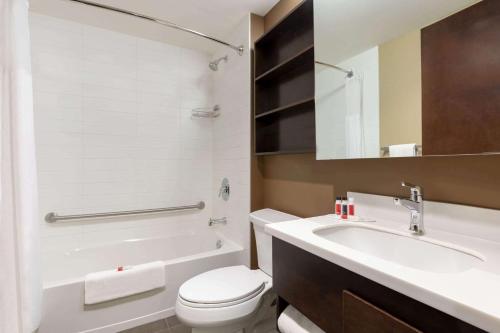 y baño con aseo blanco y lavamanos. en Microtel Inn and Suites by Wyndham Weyburn, en Weyburn