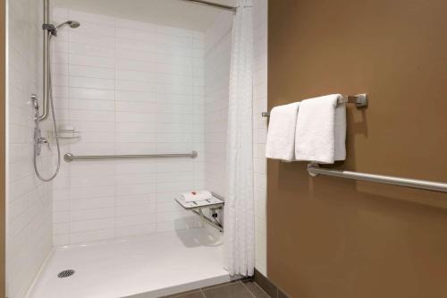 a bathroom with a shower and a toilet and towels at Microtel Inn and Suites by Wyndham Weyburn in Weyburn
