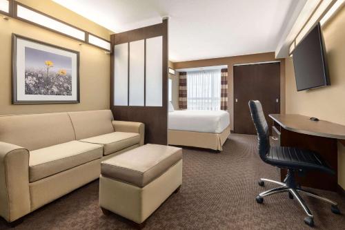 a hotel room with a couch and a bed and a desk at Microtel Inn & Suites by Wyndham Estevan in Estevan