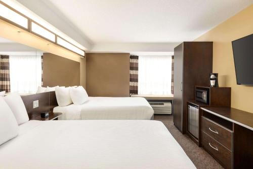 a hotel room with two beds and a television at Microtel Inn & Suites by Wyndham Estevan in Estevan