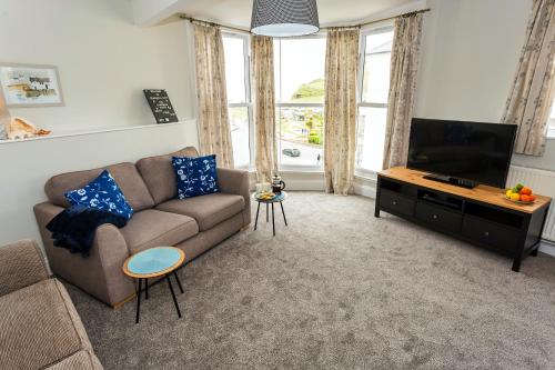a living room with a couch and a flat screen tv at Seagulls Loft, Grove Apartments in Ilfracombe