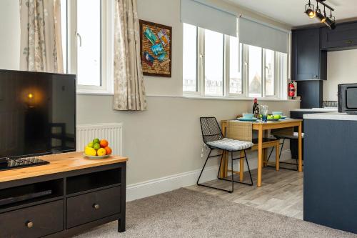 a kitchen with blue cabinets and a table with fruit on it at Seagulls Loft, Grove Apartments in Ilfracombe
