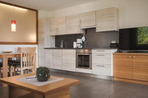 a kitchen with white cabinets and a table and a dining room at Hotel - Appartements Schmied Hans in Schenna