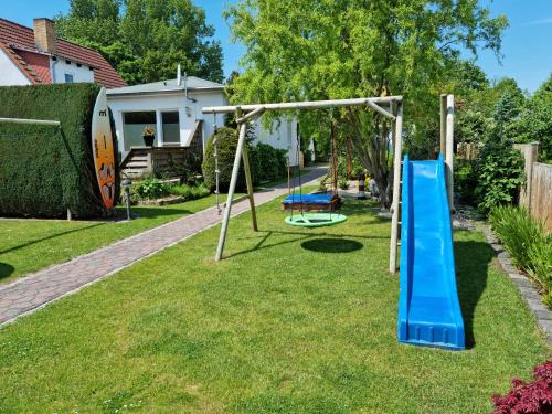 um parque infantil com um escorrega azul num quintal em Ferienhaus Leonie em Barth