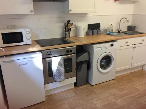 a kitchen with a stove and a washing machine at Clock House Cottage in Brook