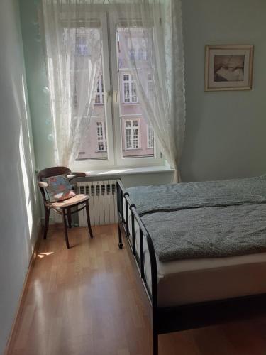 a bedroom with a bed and a chair and a window at KWATERA in Gdańsk