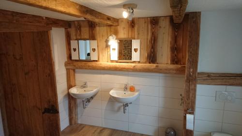 La salle de bains est pourvue de 2 lavabos et de murs en bois. dans l'établissement Urlaub auf dem Bauernhof,Landurlaub,Ferienwohnung, à Gränze