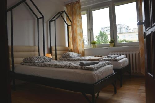 two beds in a room with two windows at Labo Apartment Metro Wierzbno in Warsaw