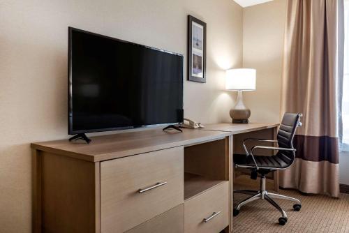 a hotel room with a television on a desk with a chair at Comfort Inn & Suites Farmington - Victor in Farmington