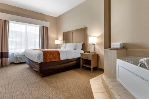 a hotel room with a bed and a bath tub at Comfort Inn & Suites Farmington - Victor in Farmington