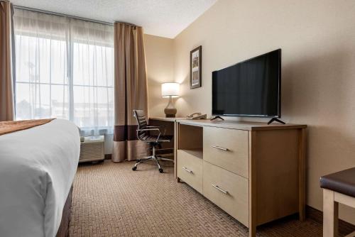 a hotel room with a bed and a television on a dresser at Comfort Inn & Suites Farmington - Victor in Farmington
