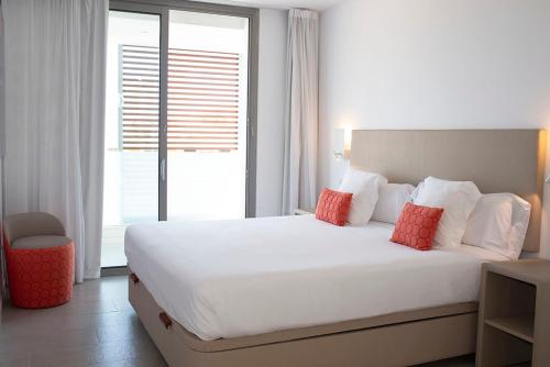 a bedroom with a large white bed with red pillows at Apartaments B-Llobet Sun & Confort in Ibiza Town