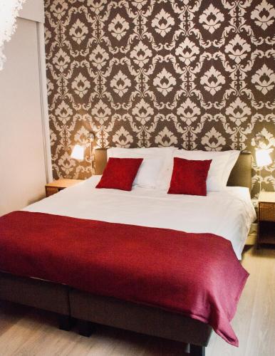 a bedroom with a large bed with red pillows at De Nachtwaker in Ieper