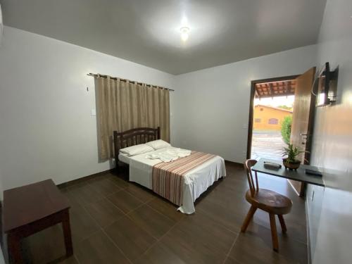 a bedroom with a bed and a desk and a window at Pousada do Lajes in Carolina