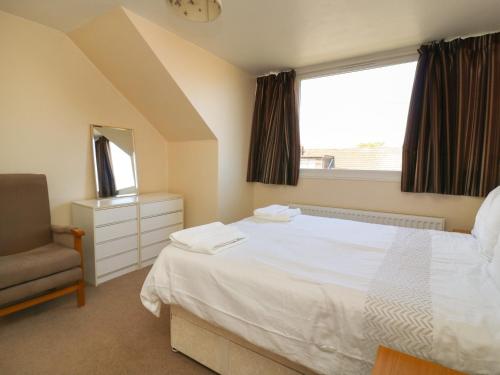 a bedroom with a bed and a chair and a window at 4 Ranby Drive in Hornsea