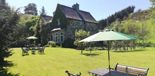 a garden with a table and an umbrella in front of a building at Penmachno Hall - self catering suite in Betws-y-coed
