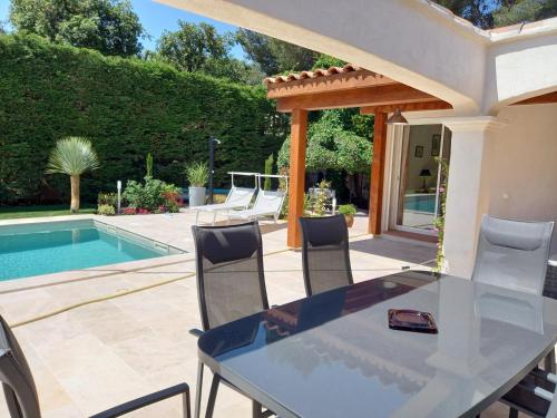 un patio avec une table et des chaises à côté d'une piscine dans l'établissement Villa au calme le brusc, à Six-Fours-les-Plages